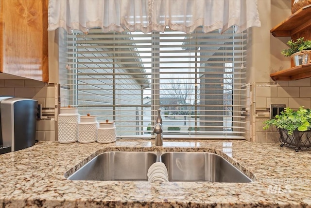 interior details featuring light stone countertops, tasteful backsplash, and a sink