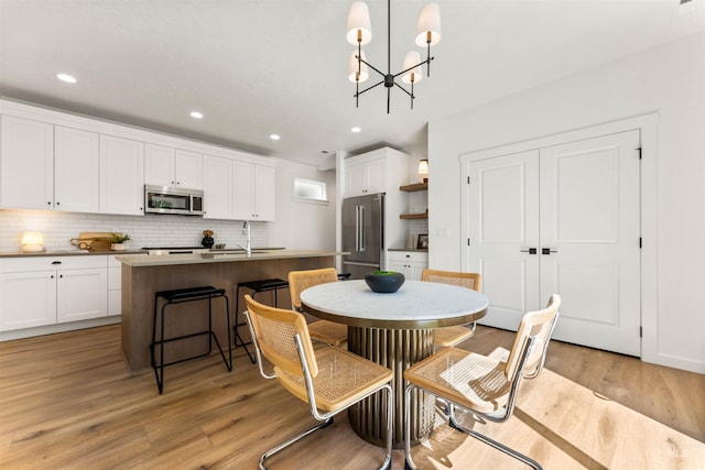 dining area featuring sink, light hardwood / wood-style floors, and an inviting chandelier