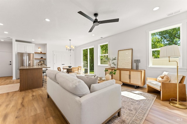 living room featuring light hardwood / wood-style floors, sink, and ceiling fan with notable chandelier