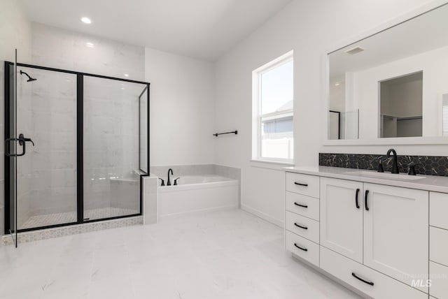 bathroom featuring plus walk in shower, a healthy amount of sunlight, and vanity