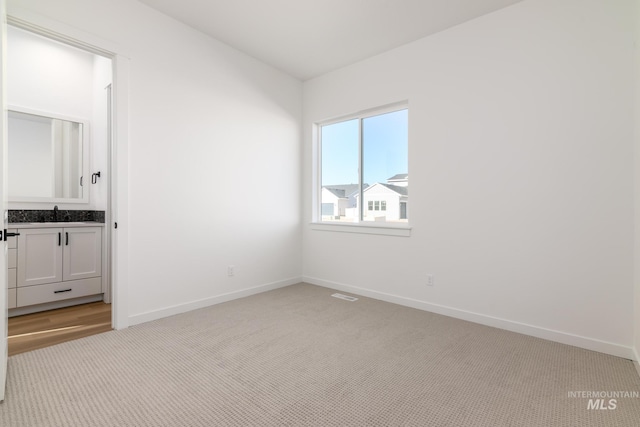 unfurnished bedroom with sink and light carpet