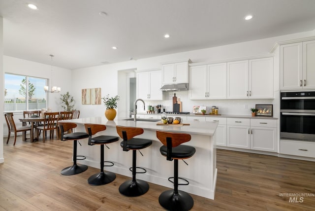 kitchen with appliances with stainless steel finishes, sink, an island with sink, and white cabinets