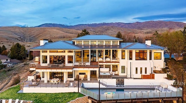 back of property featuring a mountain view, an outdoor living space, a balcony, and a patio area