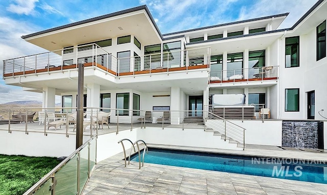 rear view of property with a fenced in pool, a balcony, and a patio