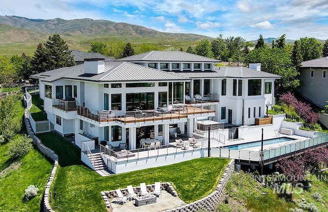 back of house with a mountain view, a balcony, a yard, and a patio