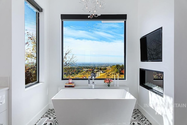 bathroom with tile patterned flooring, a tub to relax in, and a chandelier