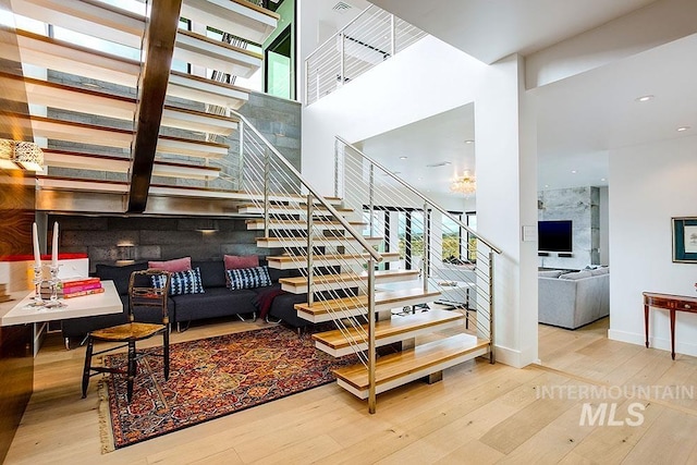 staircase with hardwood / wood-style flooring, plenty of natural light, and a high ceiling