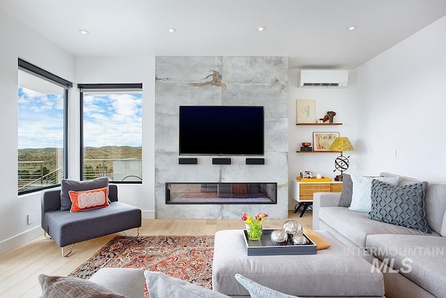 living room featuring a wall unit AC, a fireplace, and hardwood / wood-style floors