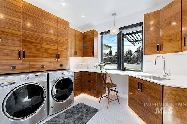 clothes washing area featuring cabinets, light tile patterned floors, sink, and washing machine and clothes dryer