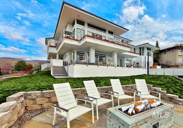 rear view of house with a patio area, a balcony, and a fire pit