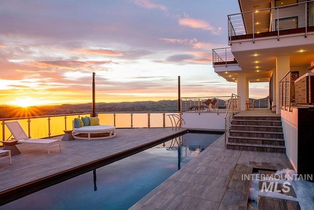 pool at dusk featuring a boat dock and a water view