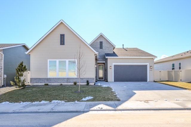 traditional-style home with concrete driveway, fence, an attached garage, a front yard, and brick siding