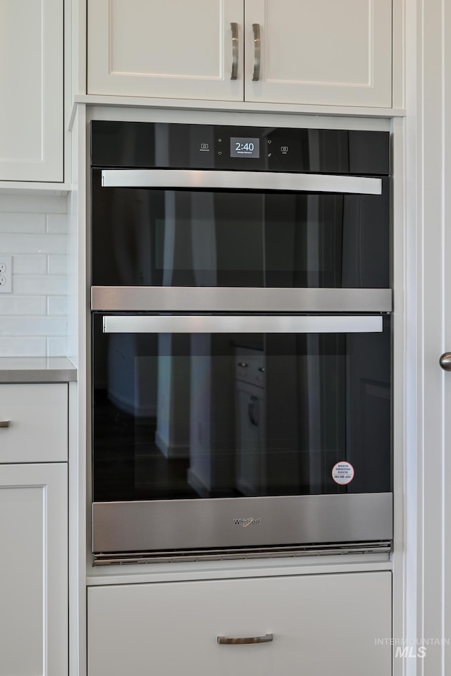 interior details featuring white cabinetry, light countertops, double oven, and backsplash