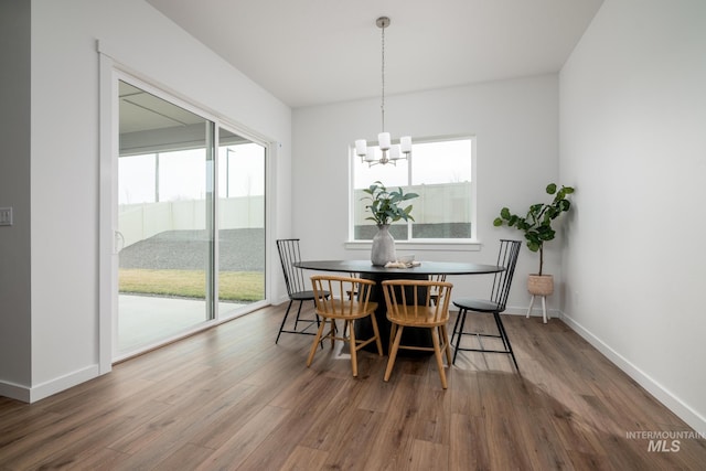 dining space featuring baseboards, wood finished floors, and a chandelier