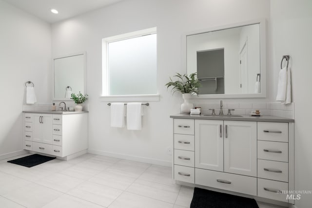bathroom featuring tile patterned floors, a sink, two vanities, and baseboards