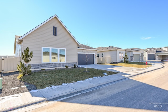 view of front of property featuring driveway, brick siding, fence, and a garage