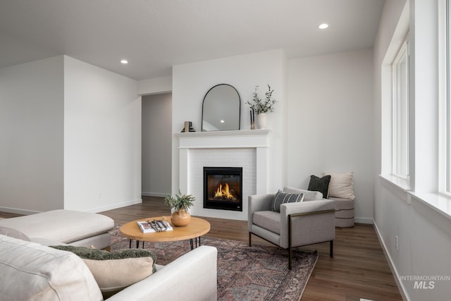 living area with baseboards, recessed lighting, wood finished floors, and a glass covered fireplace