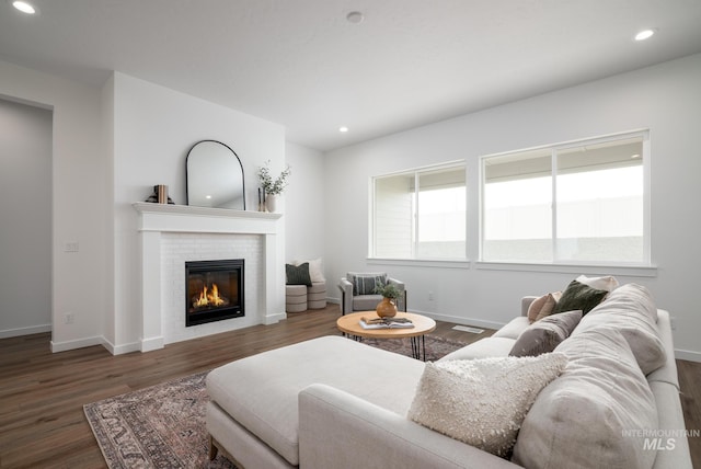 living area featuring baseboards, recessed lighting, wood finished floors, and a glass covered fireplace