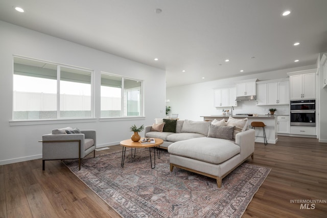 living area with dark wood-type flooring, baseboards, and recessed lighting