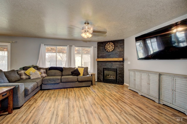 living area with a fireplace, light wood-type flooring, a wealth of natural light, and ceiling fan