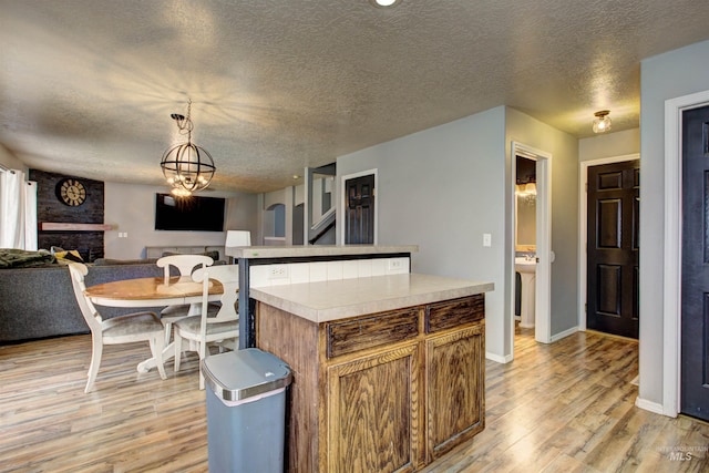 kitchen with light countertops, open floor plan, light wood finished floors, and pendant lighting