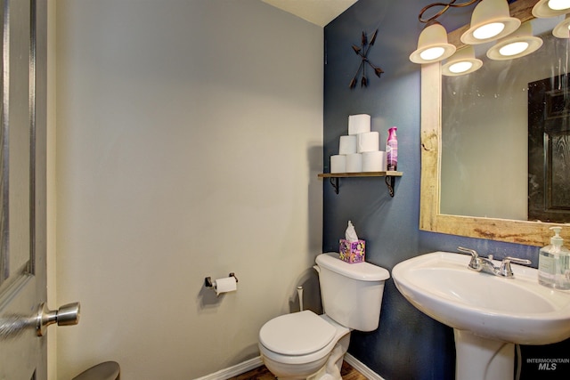 bathroom with toilet, baseboards, and a sink