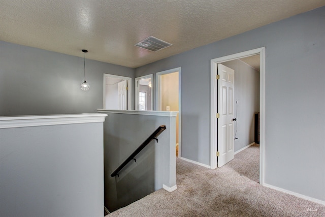 hall featuring an upstairs landing, carpet flooring, baseboards, and visible vents