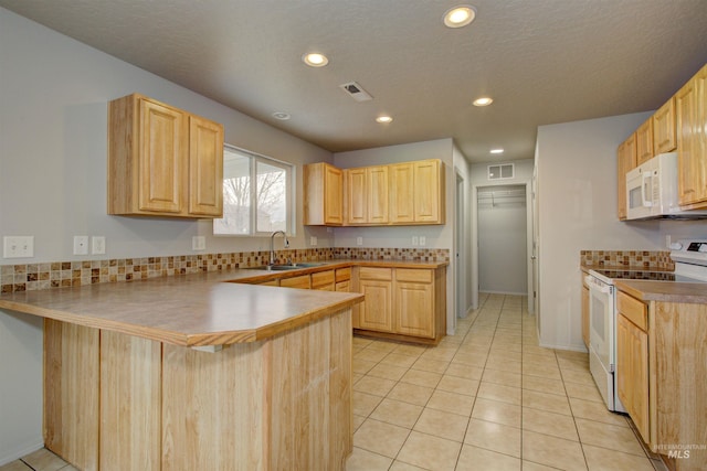 kitchen with sink, light tile patterned floors, kitchen peninsula, light brown cabinets, and white appliances