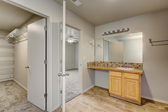 bathroom featuring wood-type flooring, decorative backsplash, and vanity