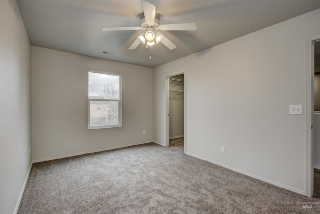 spare room featuring light carpet, ceiling fan, and a textured ceiling