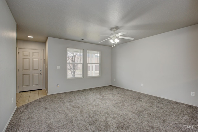 spare room with ceiling fan, light colored carpet, and a textured ceiling