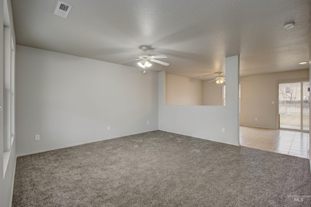 empty room with ceiling fan, light carpet, and a textured ceiling