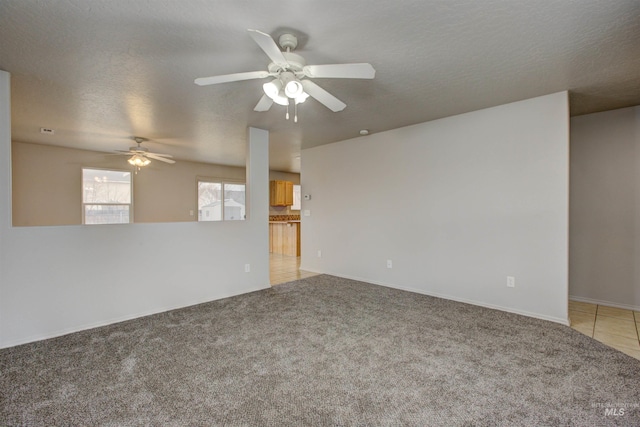 spare room with ceiling fan, light carpet, and a textured ceiling