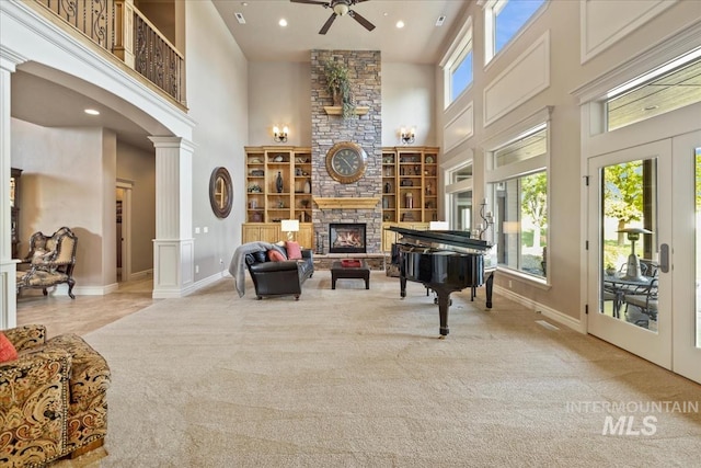 7406 Wild Horse Way, Nampa, ID 83686 - sitting room featuring carpet floors, a stone fireplace, a ceiling fan, a towering ceiling, and ornate columns