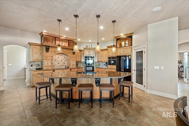 7406 Wild Horse Way, Nampa, ID 83686 - kitchen featuring backsplash, a large island, arched walkways, baseboards, and black appliances