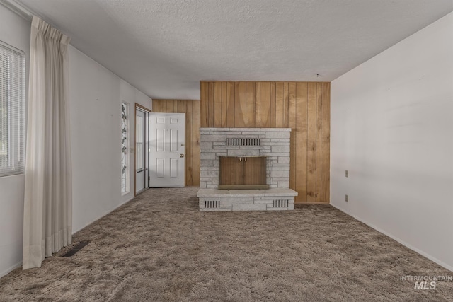 1040 N Pennsylvania Ave, Fruitland, ID 83619 - unfurnished living room with healthy amount of natural light, wooden walls, a textured ceiling, carpet, and a fireplace