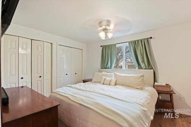 bedroom featuring ceiling fan, two closets, and wood finished floors