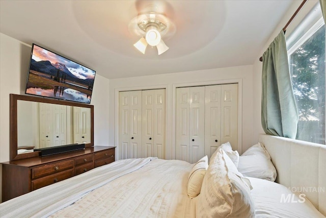 bedroom with a ceiling fan and multiple closets