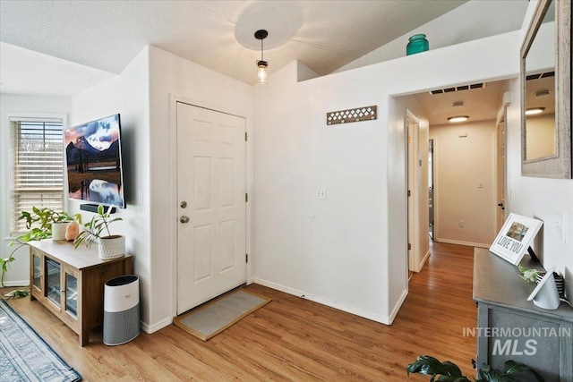 entrance foyer featuring lofted ceiling, visible vents, light wood-type flooring, and baseboards