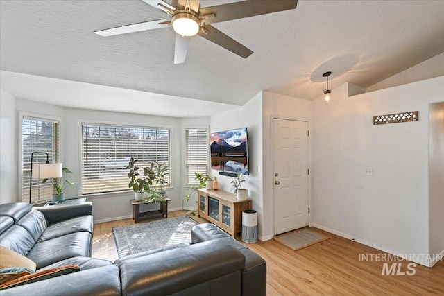 living area with light wood finished floors, baseboards, ceiling fan, lofted ceiling, and a textured ceiling