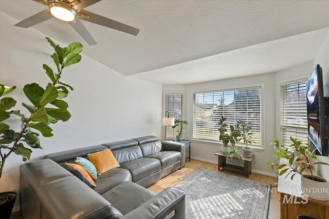 living room with lofted ceiling, a textured ceiling, wood finished floors, baseboards, and ceiling fan