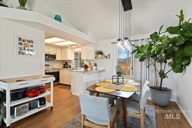 dining area featuring wood finished floors, baseboards, and vaulted ceiling