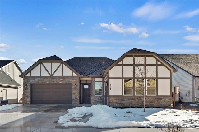 tudor-style house featuring a garage, stone siding, driveway, and stucco siding