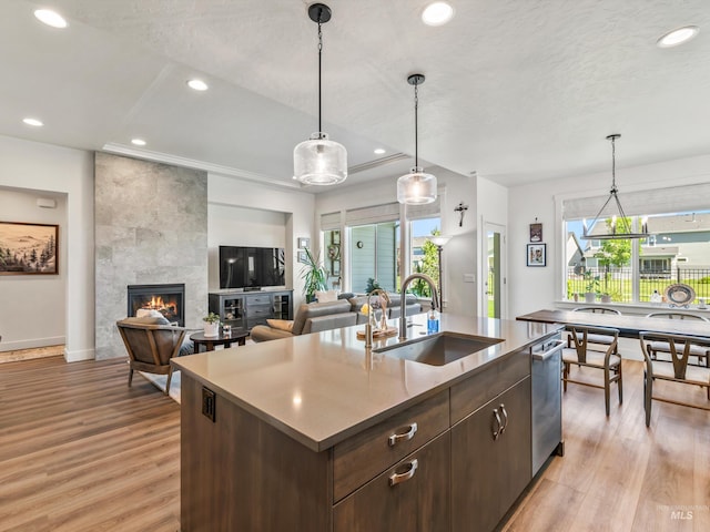 10366 Loneleaf Dr, Nampa, ID 83687 - kitchen with a sink, light wood-style floors, a tile fireplace, recessed lighting, and an island with sink