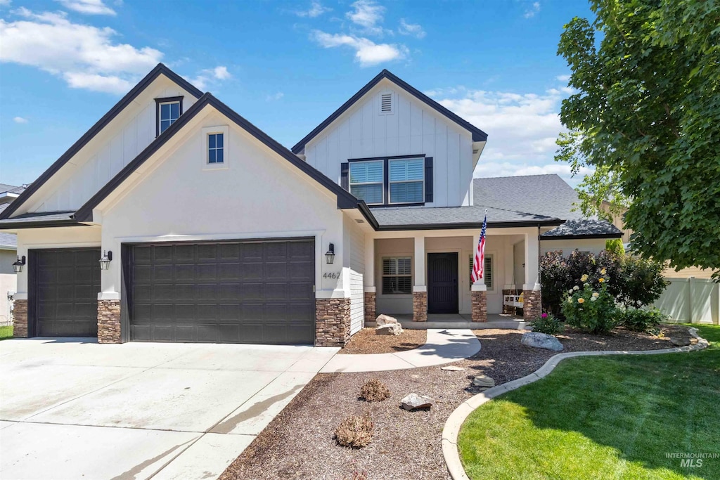 4462 N Stampede Way, Meridian, ID 83642 - view of front of property featuring stone siding, board and batten siding, a garage, a porch, and concrete driveway