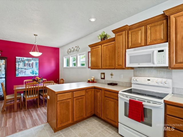 3369 W Monessen Ln, Meridian, ID 83646 - kitchen featuring white appliances, brown cabinetry, light countertops, a peninsula, and a textured ceiling