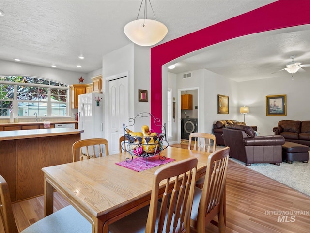 3369 W Monessen Ln, Meridian, ID 83646 - dining space featuring a textured ceiling, washer / clothes dryer, light wood-style flooring, a ceiling fan, and arched walkways