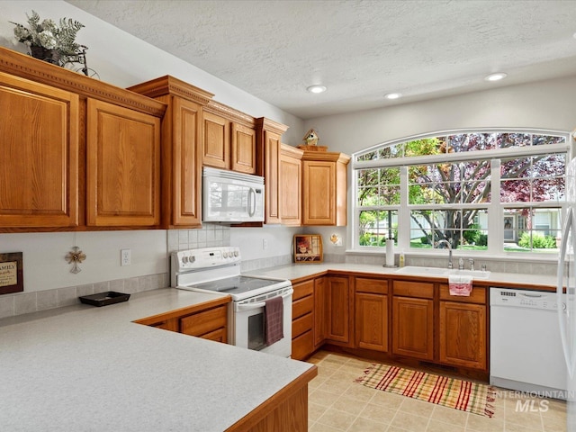 3369 W Monessen Ln, Meridian, ID 83646 - kitchen featuring white appliances, brown cabinetry, light countertops, recessed lighting, and a textured ceiling