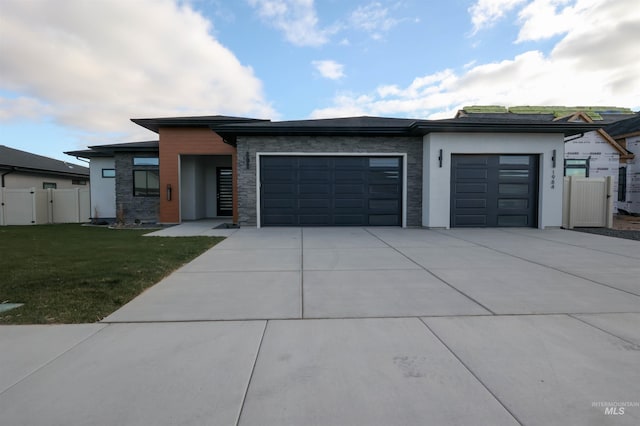 prairie-style house featuring a garage and a front lawn