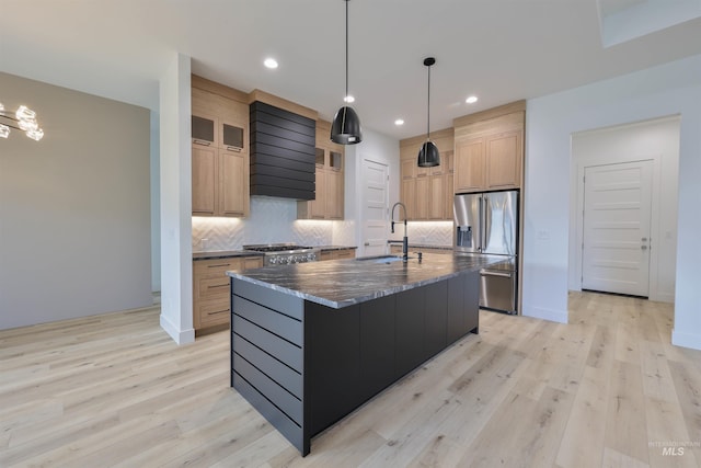 kitchen with appliances with stainless steel finishes, an island with sink, light hardwood / wood-style flooring, and sink